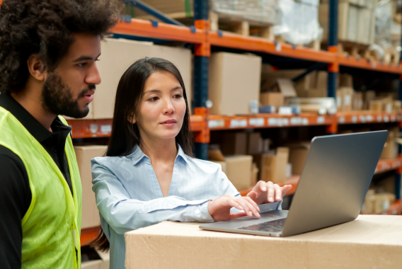 Woman and a man looking at a laptop in a warehouse Woman and a man looking at a laptop in a warehouse