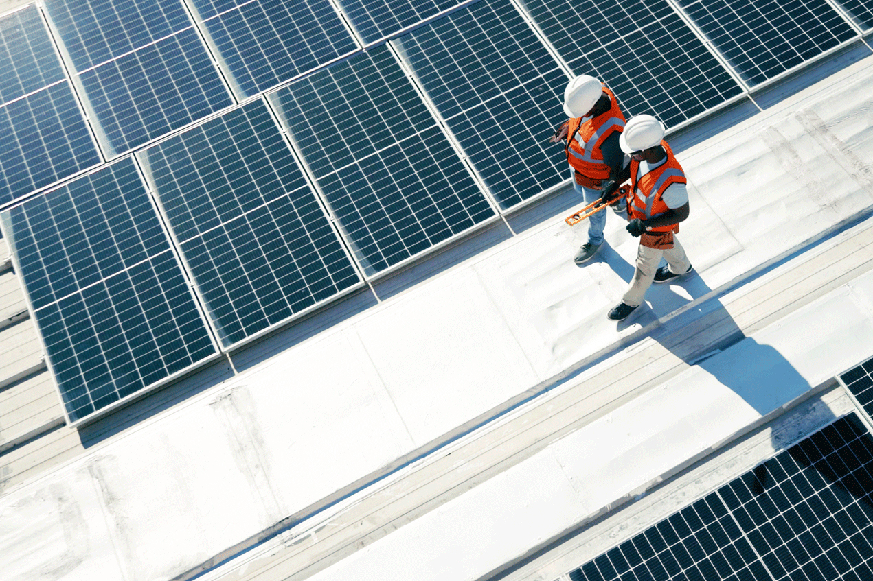  Two people walking on a roof with solar panels