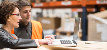 Two warehouse workers looking at a computer